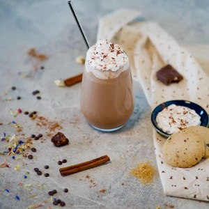 A glass of cold cocoa with cinnamon and cookies