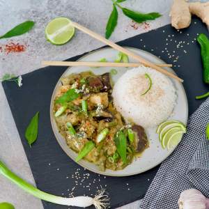 Vegan green curry on a plate with rice and condiments