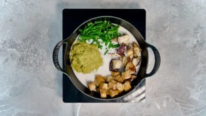 A variety of vegetables and tofu in a pot with coconut milk and green curry paste for vegan green curry